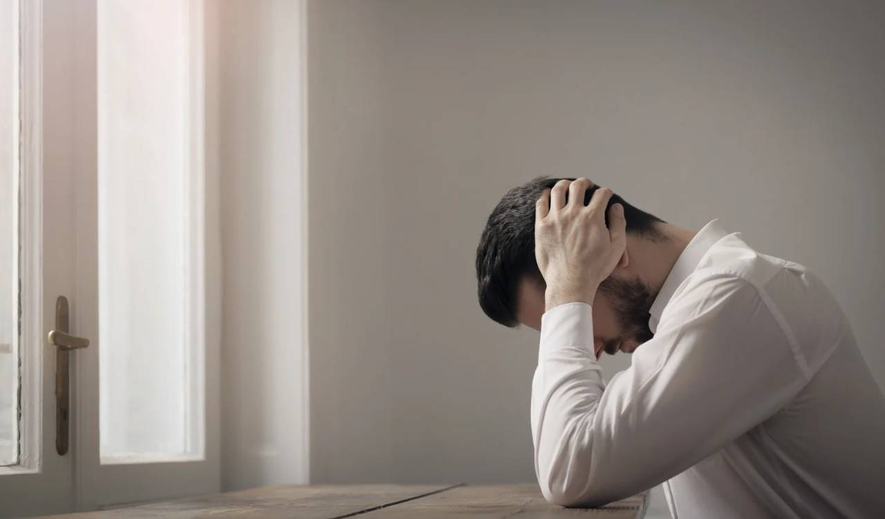 Ein Mann sitzt und fasst sich mit der Hand an den Kopf. Akupressur und das Liegen auf Akupressurmatten hilft gegen Stress und Stressbelastungsstörungen.